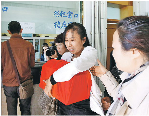 張晶（中）昨到殯儀館領取丈夫的骨灰，她緊抱冷冷的骨灰盒，悲從中來，慟哭難以抑止。